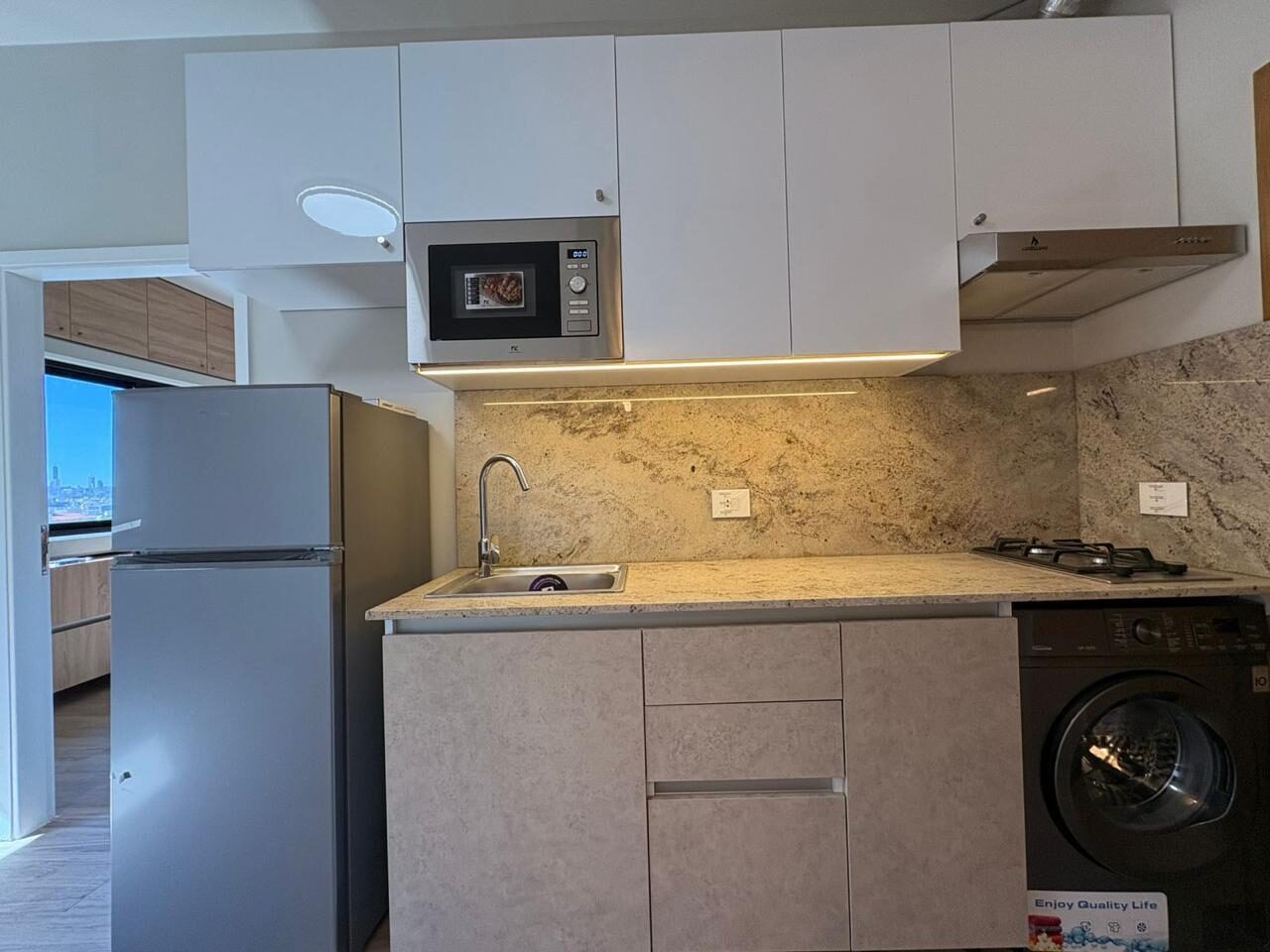Renovated studio kitchen with stone counter and washing machine